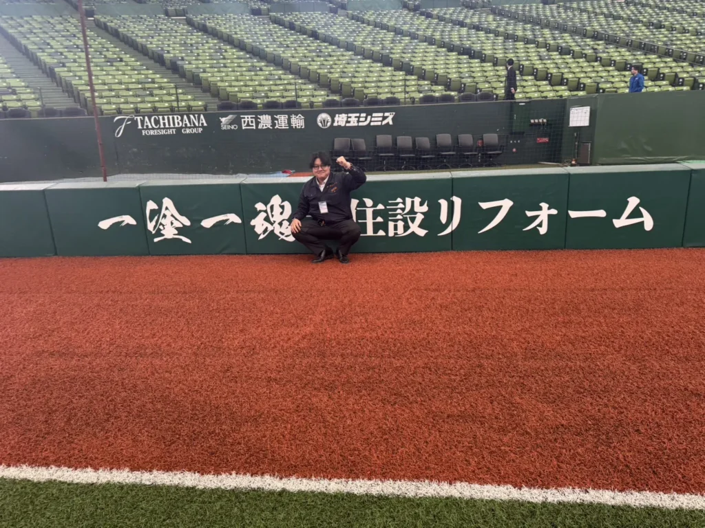 ベルーナドーム内のスポンサー掲出ロゴ前で撮影したKJリード代表の様子